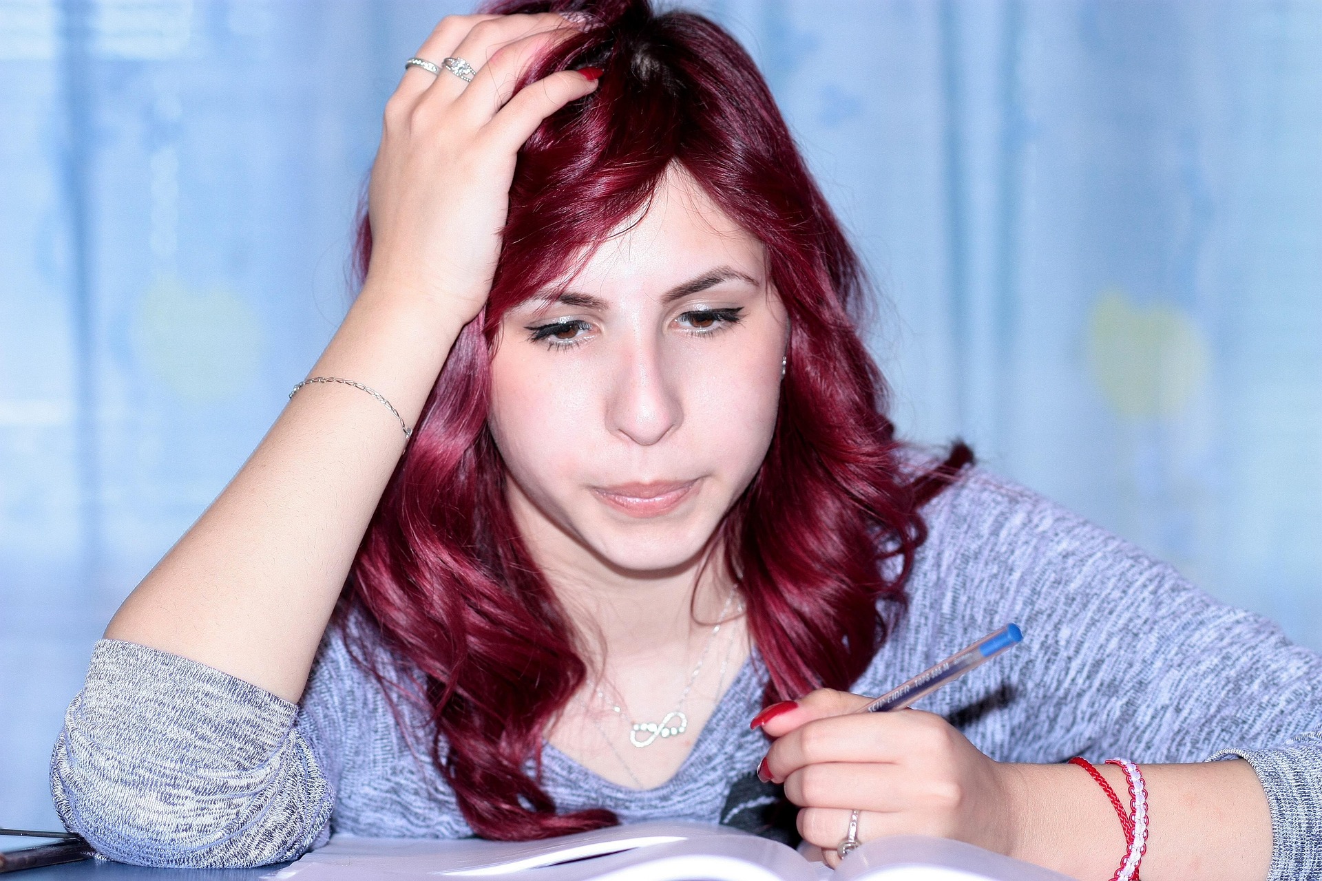 Prüfungsangst - Mädchen sitzt überfordert vor einem Stapel Bücher - Hypnose hilft bei Stress und Leistungsdruck