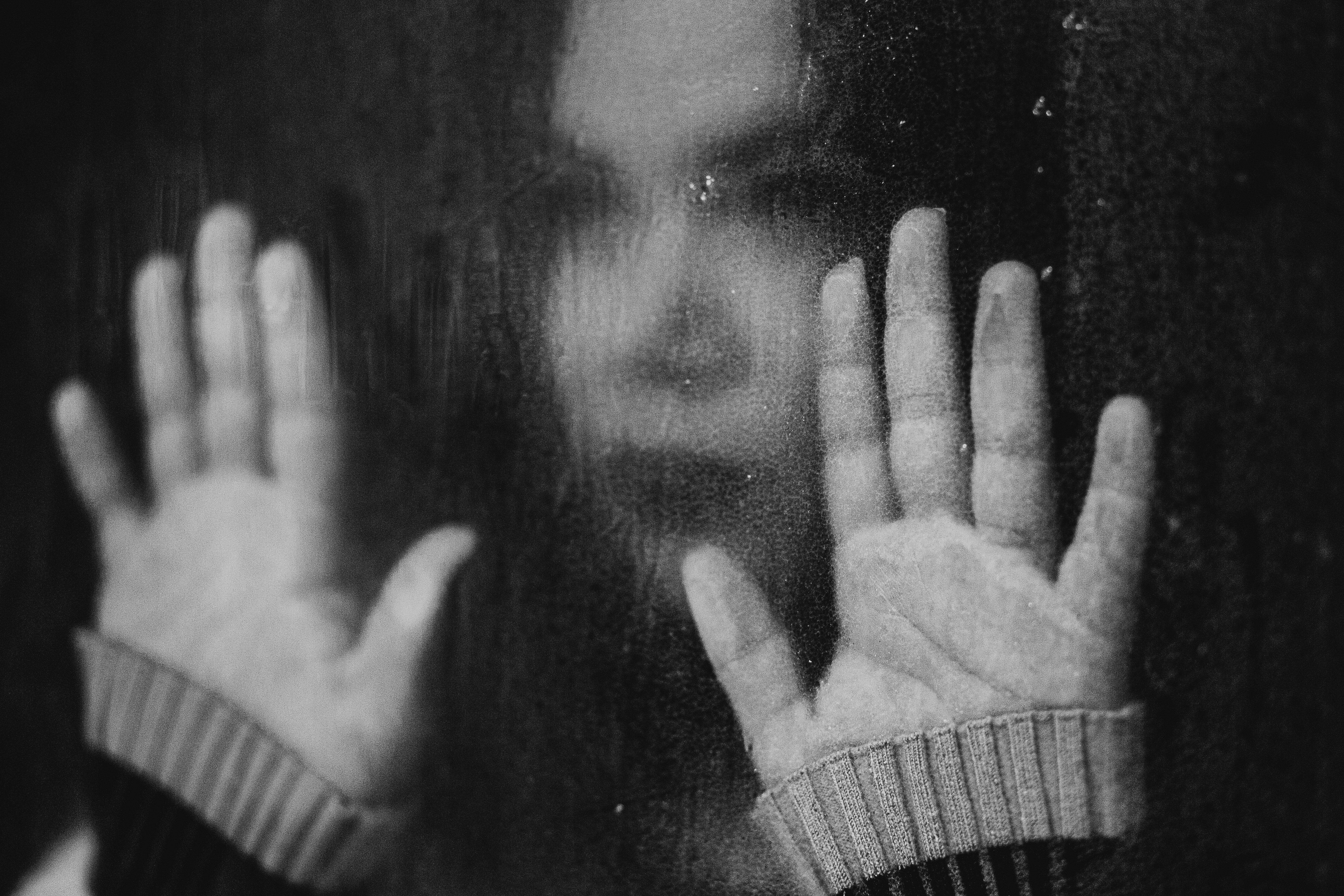 Regen an der Scheibe, Frau mit erhobenen Händen. Symbol für Depression, Hoffnungslosigkeit und Belastung.
