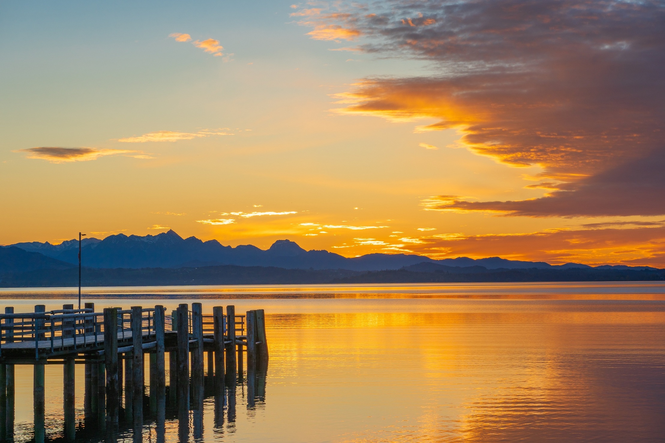 Sinnesreise an einen einsamen Steg, der in den See hineinragt. Sonnenuntergangsstimmung.